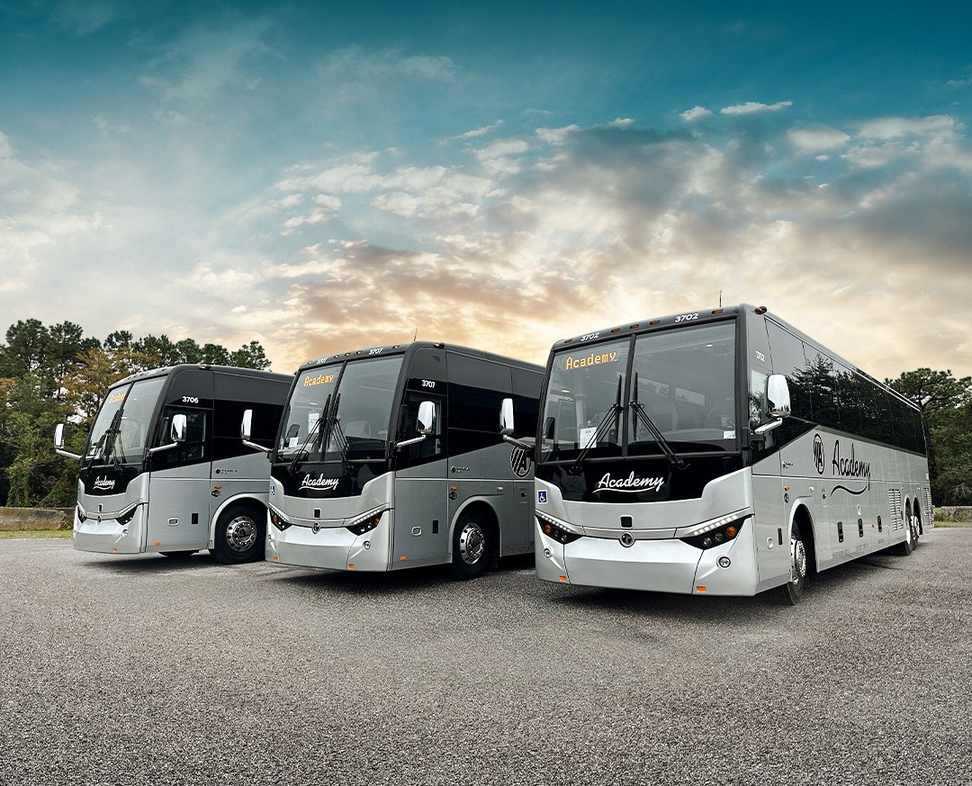 Three silver full-size motorcoaches parked side by side ready for charter service