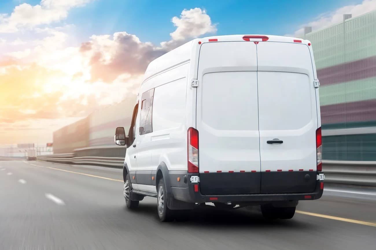 White mini bus passenger van driving on a highway toward an airport terminal
